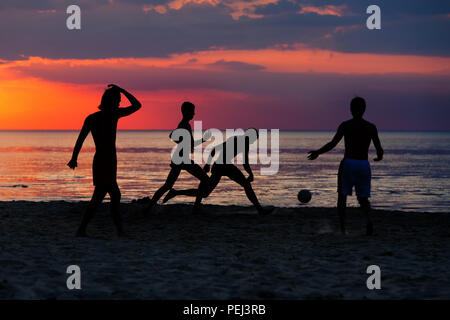 Lettland. Silhouetten der jungen Spieler mit einem Ball am Strand auf die Ostsee bei Sonnenuntergang Stockfoto