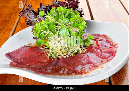 Fisch Carpaccio mit Oliven ana Salat. Auf einem weißen Teller serviert. Stockfoto
