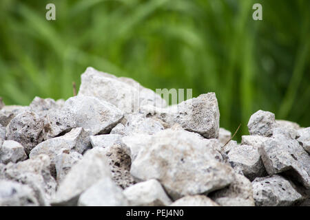 Ein Haufen von Steinen vor dem Hintergrund von Gras. Stein und Gras in Tau zerquetscht Stockfoto