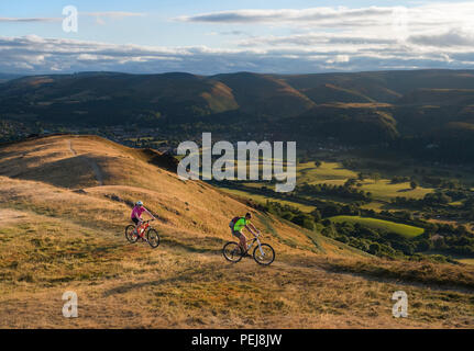 Radfahrer auf Caer Caradoc, Shropshire, mit dem Long Mynd und Church Stretton im Hintergrund zu sehen. Stockfoto