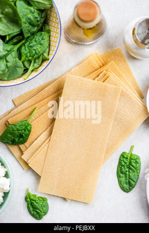 Zutaten für vegetarische Lasagne mit Spinat und Ricotta, Ansicht von oben, grauer Hintergrund Stockfoto