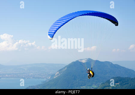 Gleitschirm fliegt in den blauen Himmel vor dem Hintergrund der Wolken. Gleitschirmfliegen in den Himmel an einem sonnigen Tag. Extrem Sport und Erholung. Stockfoto