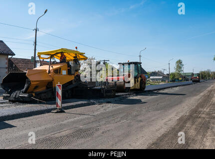 Arbeitnehmer, die Asphalt fertiger Maschine beim Straßenbau und Instandsetzung funktioniert. Ein straßenfertiger Finisher Finisher, Asphalt oder Pflaster Maschine platzieren einer Schicht von Asphalt. Belagserneuerung. Stockfoto