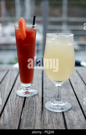 Zwei Getränke, eine Bloody Mary und eine gekühlte Ingwer Bier, draußen auf einem Holztisch Stockfoto