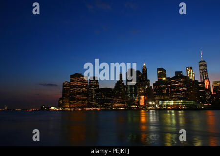 NEW YORK, NY - 03. Juli: Financial District, Lower Manhattan Skyline nach Sonnenuntergang wie aus Brooklyn Bridge Park, Brooklyn gesehen Stockfoto