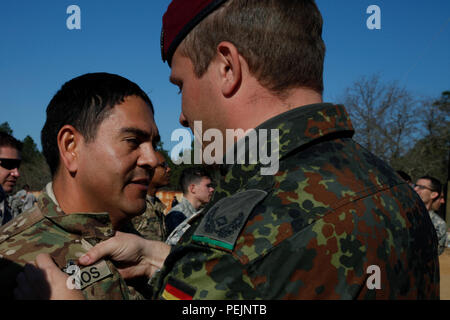 U.S. Army Staff Sgt. Mario Recinos, zu 9.: ein Unternehmen, das militärische Informationen Support Bataillons, erhält er den Deutschen springen Flügel aus Deutschen jumpmaster Maj Daniel Labussch auf Luzon Drop Zone während ein Betrieb für die 18. jährlichen Randy Oler Memorial Betrieb Spielzeug Fallen, bewirtet durch die US-Armee die zivilen Angelegenheiten & psychologische Operations Command (Airborne), im Camp Mackall, N.C., Dez. 8, 2015 zugeordnet. Betrieb Spielzeug Drop ist der weltweit größte kombinierten Betrieb und gemeinsame Aus- und Fortbildung mit sieben Partner - nation Fallschirmjäger teilnehmenden und Soldaten erlaubt, die Möglichkeit, Kindern zu helfen Stockfoto