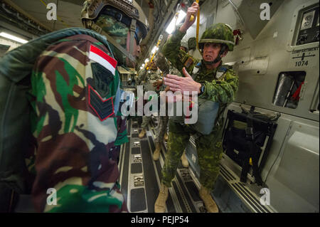 Kanadische Streitkräfte Brig. Gen. Simon C. Hetherington, (rechts) Stellvertretender kommandierender General der Operationen für die 18 Airborne Corps, zeigt an, dass alle fallschirmausrüstung zu indonesischen Jumpmaster Sgt aktiviert ist. Tarto Sutaro während ein Betrieb für den Betrieb Spielzeug Drop an Ft. Bragg, N.C., Dez. 5, 2015. Gehostet von US-Armee die zivilen Angelegenheiten & psychologische Operations Command (Airborne), Operation Spielzeug Drop ist der weltweit größte kombinierten Betrieb mit sieben Partner - nation Fallschirmjäger teilnehmenden und Soldaten erlaubt, die Möglichkeit, Kindern in Not zu helfen, überall Spielzeug für die Uhr empfangen Stockfoto