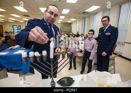 Oberstleutnant Jaakow B. Bindell, Links, das New-jersey National Guard State Kaplan, leuchtet die Shamash, oder Erziehungsberechtigten Kerze, auf der Menorah während einer Hanukkah Kerzenschein Zeremonie an der Hauptbasis Kapelle, Joint Base Mc Guire-Dix - Lakehurst, New Jersey, Dez. 9, 2015. Die Veranstaltung wurde gemeinsam von der Hauptbasis Kapelle und Jüdische Kriegsveteranen Post 126 gefördert. Chanukka erinnert an die Umwidmung der Heilige Tempel in Jerusalem während der maccabean Revolte. Chanukka ist für acht Nächte und Tage beobachtet, beginnend mit dem 25. Kislew nach dem Hebräischen Kalender, die jederzeit von Ende November auftreten können. Stockfoto