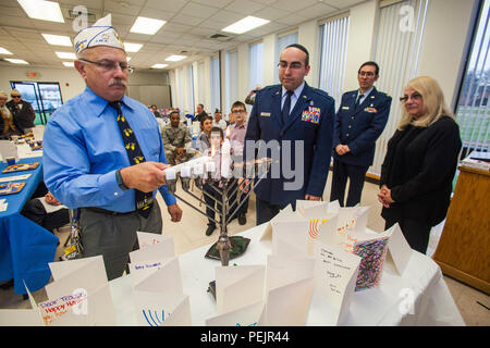 Larry Rosenthal, Links, Commander, jüdische Kriegsveteranen, leuchtet eine der vier Kerzen auf der Menorah - Für jeden Tag von Hanukkah bei Kerzenschein Zeremonie an der Hauptbasis Kapelle, Joint Base Mc Guire-Dix - Lakehurst, New Jersey, Dez. 9, 2015. Die Veranstaltung wurde gemeinsam von der Hauptbasis Kapelle und Jüdische Kriegsveteranen Post 126 gefördert. Chanukka erinnert an die Umwidmung der Heilige Tempel in Jerusalem während der maccabean Revolte. Chanukka ist für acht Nächte und Tage beobachtet, beginnend mit dem 25. Kislew nach dem Hebräischen Kalender, die jederzeit von Ende November auftreten können Stockfoto