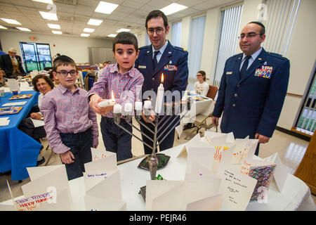 United States Air Force Reserve Maj Menashe Miller, zweiter von rechts, ein Kaplan, Uhren seine Söhne die vierte Kerze auf der Menorah - Für jeden Tag von Hanukkah bei Kerzenschein Zeremonie an der Hauptbasis Kapelle, Joint Base Mc Guire-Dix - Lakehurst, New Jersey, Dez. 9, 2015 Licht. Die Veranstaltung wurde gemeinsam von der Hauptbasis Kapelle und Jüdische Kriegsveteranen Post 126 gefördert. Chanukka erinnert an die Umwidmung der Heilige Tempel in Jerusalem während der maccabean Revolte. Chanukka ist für acht Nächte und Tage beobachtet, beginnend mit dem 25. Kislew nach dem Hebräischen Kalender, die Trade Boxes Stockfoto