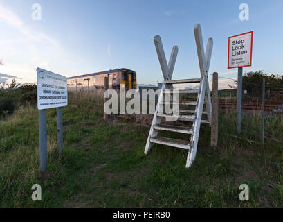 Eine nördliche Bahn Klasse 156 Sprinter Zug passiert den öffentlichen Fuß Überfahrt über die Bahnstrecke Kirkby In Furness mit Stop look Listen unterschreiben. Stockfoto