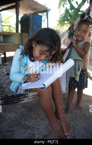 Kinder sitzen auf einer Hängematte und singen das Alphabet, während sie am 7. Dezember 2015 in einer Grundschule auf Falalop Island im Ulithi-Atoll, Föderierte Staaten von Mikronesien, ihre Schreibfähigkeiten üben. Die Schule wurde im März 2015 durch den Taifun Maysak stark beschädigt und nutzt weiterhin improvisierte Lernräume. Die Aktivität ist Teil der Bemühungen der Gemeinschaft, die Bildung für Jugendliche während der Erholung nach dem Sturm direkt über das Atoll aufrechtzuerhalten. Stockfoto