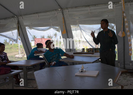 Eine Landwirtschaftsklasse findet in einem temporären Klassenzelt an der Outer Islands High School auf Falalop Island im Ulithi Atoll, Föderierte Staaten von Mikronesien statt. Das Zelt wurde für den Gebrauch gespendet, nachdem der Taifun Maysak im März 2015 die Schulgebäude stark zerstörte. Die Studenten erhalten Unterricht in Agrarwissenschaften während der ständigen Erholung, indem sie improvisierte Lernräume nutzen, um die aus- und Weiterbildung auf der Insel fortzusetzen. Stockfoto