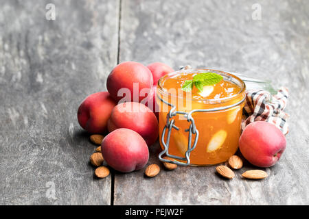 Red Aprikosenmarmelade mit Mandeln in einer klaren Glas Glas auf hölzernen Tisch Stockfoto