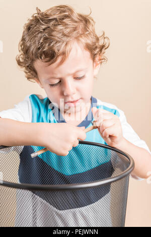 Konzept der zurück in die Schule. Kind schärfen einen Bleistift neben einem Papierkorb. Stockfoto