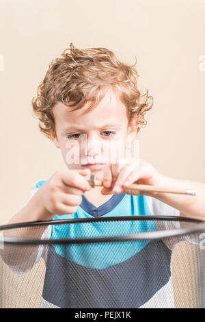 Konzept der zurück in die Schule. Kind schärfen einen Bleistift neben einem Papierkorb. Stockfoto