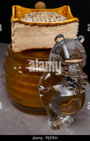 Honig im Glas container wie ein Bär und Honigseim, Holzstab geformt Stockfoto