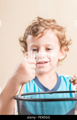 Konzept der zurück in die Schule. Kind schärfen einen Bleistift neben einem Papierkorb. Stockfoto