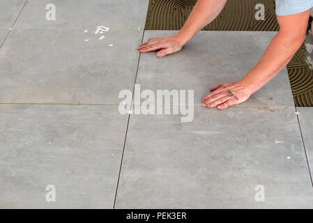 Die Hände Der fliesenleger sind Festlegung der keramischen Fliese auf dem Boden. Stockfoto