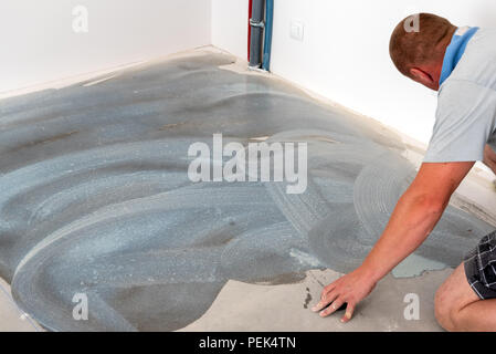 Ein Arbeiter bringt die Stiftung unter der Keramikfliesen. Home Renovierung Stockfoto