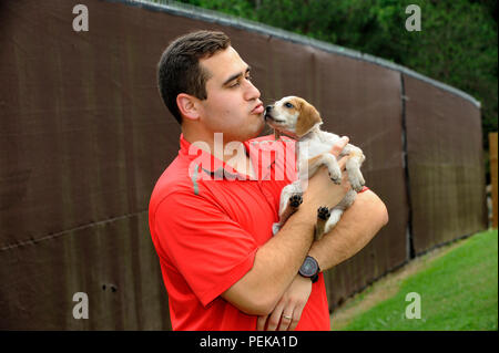 Ein junger Welpe, der zur Adoption bereit ist, wird von einem Latino-Mitarbeiter eines lokalen Tierheims in Gainesville, Georgia, getröstet © Billy Grimes/Alamy.com Stockfoto