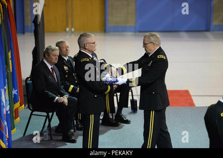 Pensionierte US-Armee Generalmajor Murray Sagsveen, früher von der North Dakota Army National Guard, rechts, präsentiert die Vereinigten Flaggenstaaten Generalmajor David Sprynczynatyk, der scheidende North Dakota Adjutant General, die während eines Befehls Zeremonie als North Dakota reg. Jack Dalrymple, sitzt ganz links, und Gen. Frank Gras, Chef der National Guard Bureau, zweiter von links, am Raymond J. Bohn Armory, Bismarck, N.D., Dez. 13, 2015. Generalmajor Al Dohrmann ist Kommando aus Sprynczynatyk und ist neben Gras sitzt, aber nicht in der Abbildung nicht sichtbar. Sagsveen hat eine bedeutende. Stockfoto