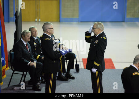 Pensionierte US-Armee Generalmajor Murray Sagsveen, früher von der North Dakota Army National Guard, rechts, begrüßt Generalmajor David Sprynczynatyk, der scheidende North Dakota Adjutant General, auf die ihn die Vereinigten Flaggenstaaten bei einem Befehl Zeremonie als North Dakota reg. Jack Dalrymple, sitzt ganz links, und Gen. Frank Gras, Chef der National Guard Bureau, zweiter von links, am Raymond J. Bohn Armory, Bismarck, N.D., Dez. 13, 2015. Generalmajor Al Dohrmann ist Kommando aus Sprynczynatyk und ist neben Gras sitzt, aber nicht in der Abbildung nicht sichtbar. Sagsveen hat Biene Stockfoto