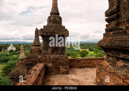 Thisa-Wadi-Tempel Bagan Myanmar // BAGAN, Myanmar – Ein Blick von den oberen Terrassen des thisa-Wadi-Tempels (auch bekannt als Thissa-Wadi-Tempel) überblickt die weitläufige Bagan-Ebene. Nach epigraphischen Beweisen aus dem Jahr 1334 n. Chr. wurde dieser dreistöckige Tempel in der postkaiserlichen Zeit errichtet, fast ein halbes Jahrhundert nach dem Fall des heidnischen Königreichs. Der Tempel ist als Denkmal Nr. 918 in Pierre Pichards umfangreichem archäologischem Inventar der archäologischen Zone Bagan katalogisiert. Trotz umfangreicher Renovierungsarbeiten mit verzierten Außendekorationen ist dieses Wadi weiterhin eines von ihnen Stockfoto