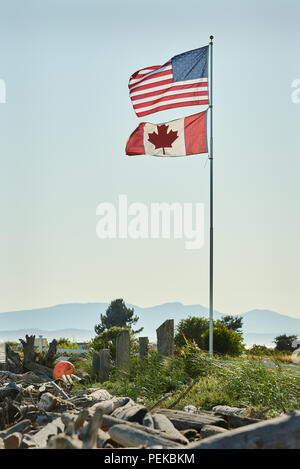 US-amerikanischen und kanadischen Flagge. US- und Kanadische Fahnen wehen in Point Roberts, Washington State. Mt Baker im Hintergrund. Stockfoto