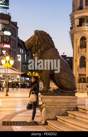 SKOPJE, MAZEDONIEN - Oktober 24, 2015: Junge Frau witing unter einem Lion Statue, Teil der Skopje 2014 Projekt. 2012 eröffnet, wurde es ein t Stockfoto