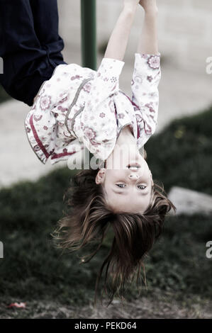 Unschuldige kleine Mädchen spielen mit der Oberseite nach unten hängend auf der Monkey Bars. Stockfoto