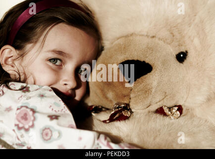 Unschuldige kleine Mädchen kuscheln eine riesige Teddybären. Stockfoto