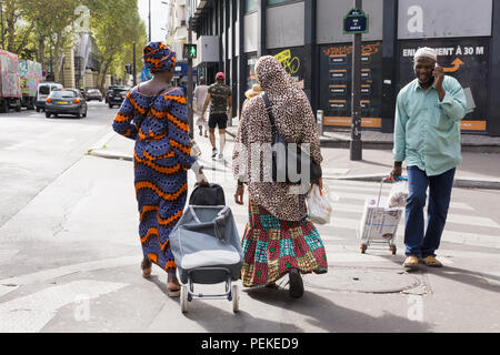 Eine Straßenszene in der stalingrad Gegend von Paris - Frauen afrikanischer Herkunft in traditioneller Kleidung wandern und Plaudern. Frankreich. Stockfoto