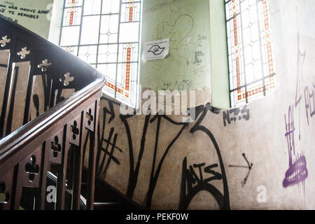 Hintergrund von Kohle, Holz Treppen eines verlassenen Vintage House mit Graffiti an den Wänden und Buntglasfenstern. Keine Menschen. Stockfoto
