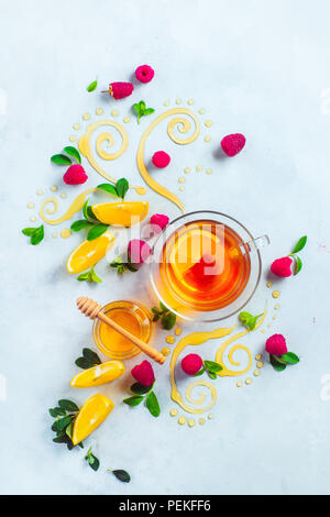 Honig Kaffee von oben. Dekorative Honig wirbelt, Zitronenscheiben, Beeren und Kaffee in einem Glas Schale auf einem weißen Holz- Hintergrund mit kopieren. Kreative Küche flach Stockfoto