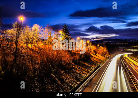 Lange Belichtung Night Shot einer Autobahn aus der Region Freiburg in der Schweiz, mit gelben Fahrzeug leichte Wanderwege und der öffentlichen Beleuchtung Stockfoto