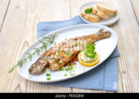 Gebratene Forelle mit Mandeln, Butter und Sahne Meerrettich auf einem weißen Fischplatte serviert. Stockfoto