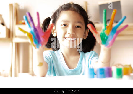 Das kleine Mädchen zeigt Farbe auf Hände mit Lächeln und Freude gemalt. Wählen Sie Fokus geringen Tiefenschärfe und unscharfen Hintergrund Stockfoto