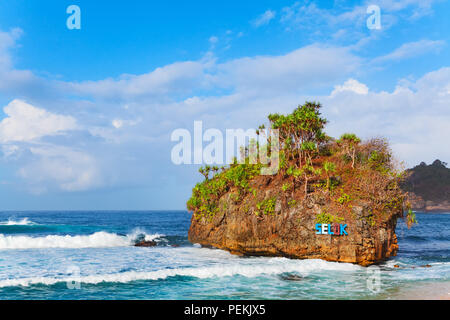 Beliebtes Reiseziel in Ost Java - Pantai Selok Strand. Malerischer Blick auf kleine Insel, Meer Brandung an der Küste Reef. Sommer Familienurlaub Stockfoto