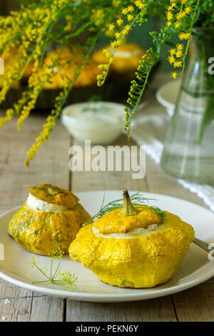 Pattypan Squash oder Kürbisse, gefüllt mit Ricotta mit Basilikum und Dill und serviert mit saurer Sahne Soße. Vegetarisches Essen, rustikaler Stil, selektiven Fokus. Stockfoto