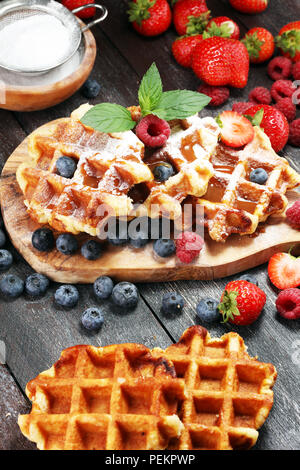 Traditionelle belgische Waffeln mit frischer Minze, Zucker und Himbeeren, Blaubeeren und Erdbeeren. Stockfoto