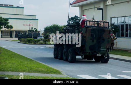 Santa Claus kommt in ein leicht gepanzertes Fahrzeug für den Fall, Santa's Little Helper, auf Camp Hansen, Okinawa, Japan, Dez. 12, 2015. Die Veranstaltung hatte auch der Weihnachtsmann schnell Seil aus einem Hubschrauber, Kunstschnee, eine Hüpfburg, Kinderschminken und Essen serviert. Der LAV ist mit Combat Assault Bataillon, 3rd Marine Division, III Marine Expeditionary Force. (U.S. Marine Corps Foto von Cpl. Tyler S. Giguere/Freigegeben) Stockfoto