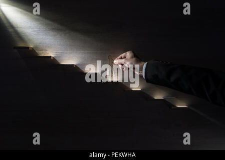 Geschäftsmann klettern die Schritte zum Erfolg mit Papier silhouette Ausschnitte aus einem Mann und einer menschlichen Hand helfen ihm in Richtung des Lichts klettern. Stockfoto