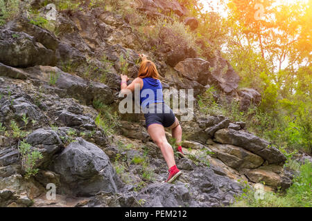 Junge rothaarige Mädchen Bergsteiger in Sport Kleidung klettert auf Felsen nach oben in den Bergen der Altai ohne Ausrüstung und Versicherung Stockfoto