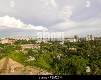 Luftaufnahmen von grauen Wolken im Himmel mit grünen Bäumen, unter ihnen an einem sonnigen Tag in einer grossen Stadt mit Wolkenkratzern und ein Standort für den Bau wit Stockfoto