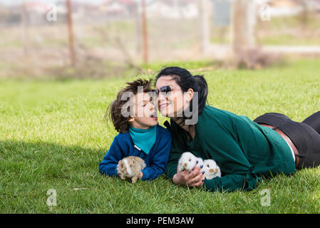 Schönen Mutter und Sohn Spaß im Garten und halten wenig Bunnys Stockfoto