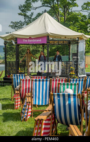 Publikum in Liegestühlen beobachten Musik am Musikpavillon durch die Gruppe von 3 Sängerinnen (Trio) - RHS Chatsworth Flower Show, Derbyshire, England, Großbritannien Stockfoto