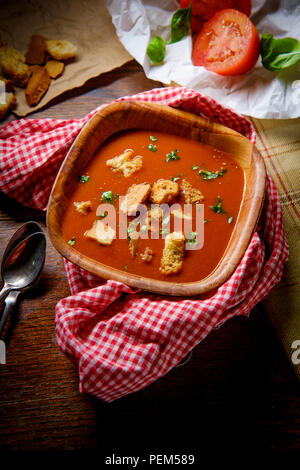 Frische Hot Tomate Basilikum Suppe mit Croutons in dunklen stimmungsvolle Beleuchtung Stockfoto