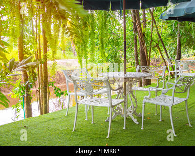 White vintage Stahl Tabelle mit hohen Dach auf Kunstrasen Stock in den Garten im Land gesetzt. Stockfoto