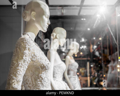 Weiße weibliche Schaufensterpuppe in Hochzeit Kleid im Schaufenster. Braut Kleider auf die Puppen in Hochzeit Fenster mit Licht auf Hochzeit Anzug shop backgr Stockfoto